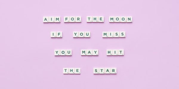 Inspirational message using Scrabble tiles on a pastel background.